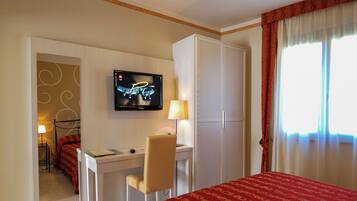Ein Hotelzimmer mit einem Bett, einem Schreibtisch mit Stuhl, einem Fernseher und einem Kleiderschrank.