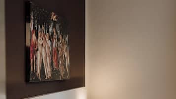 A hotel room with a bed, two bedside lamps, a painting on the wall, and a nightstand with a phone.