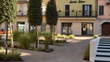 Hotel "Hotel Eden" met een geplaveid binnenterrein, bomen en een trap naar de ingang.