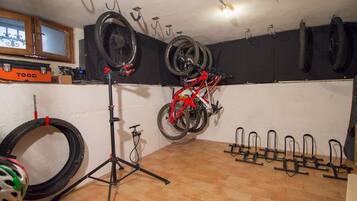 A room with a bicycle mounted on a stand, a wall-mounted tire rack, and a bicycle repair stand.