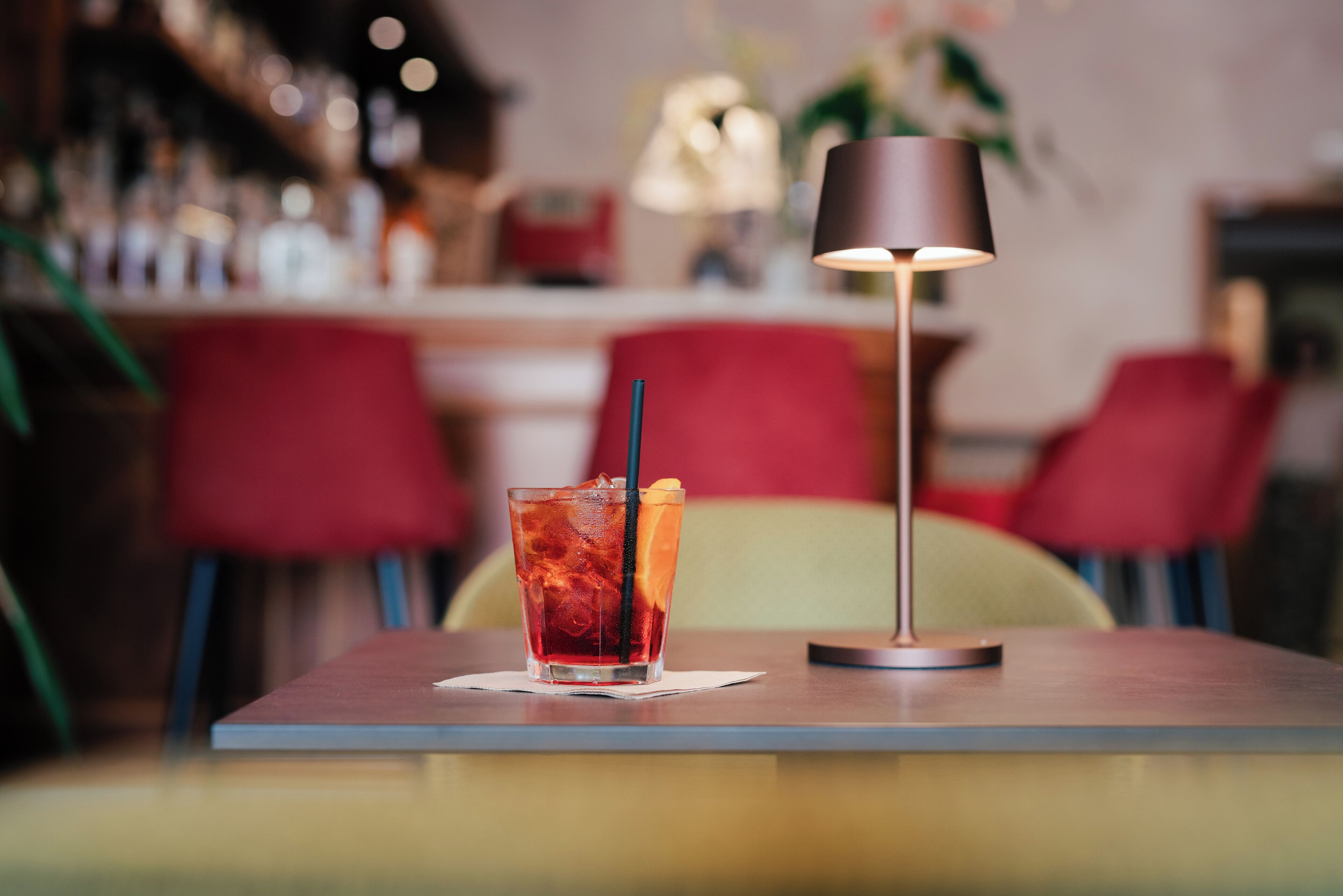 A table with a drink and a lamp.