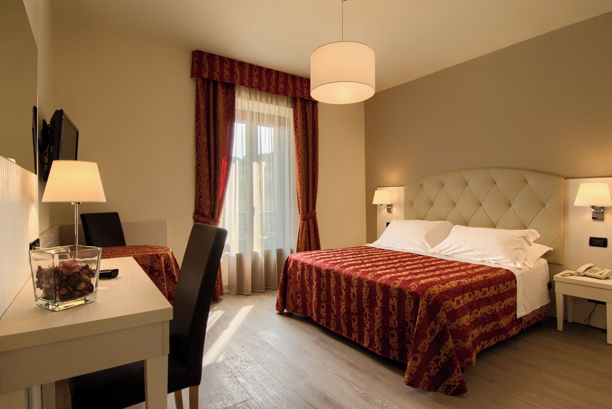 Una habitación de hotel con cama, mesitas de noche, un escritorio y una silla.