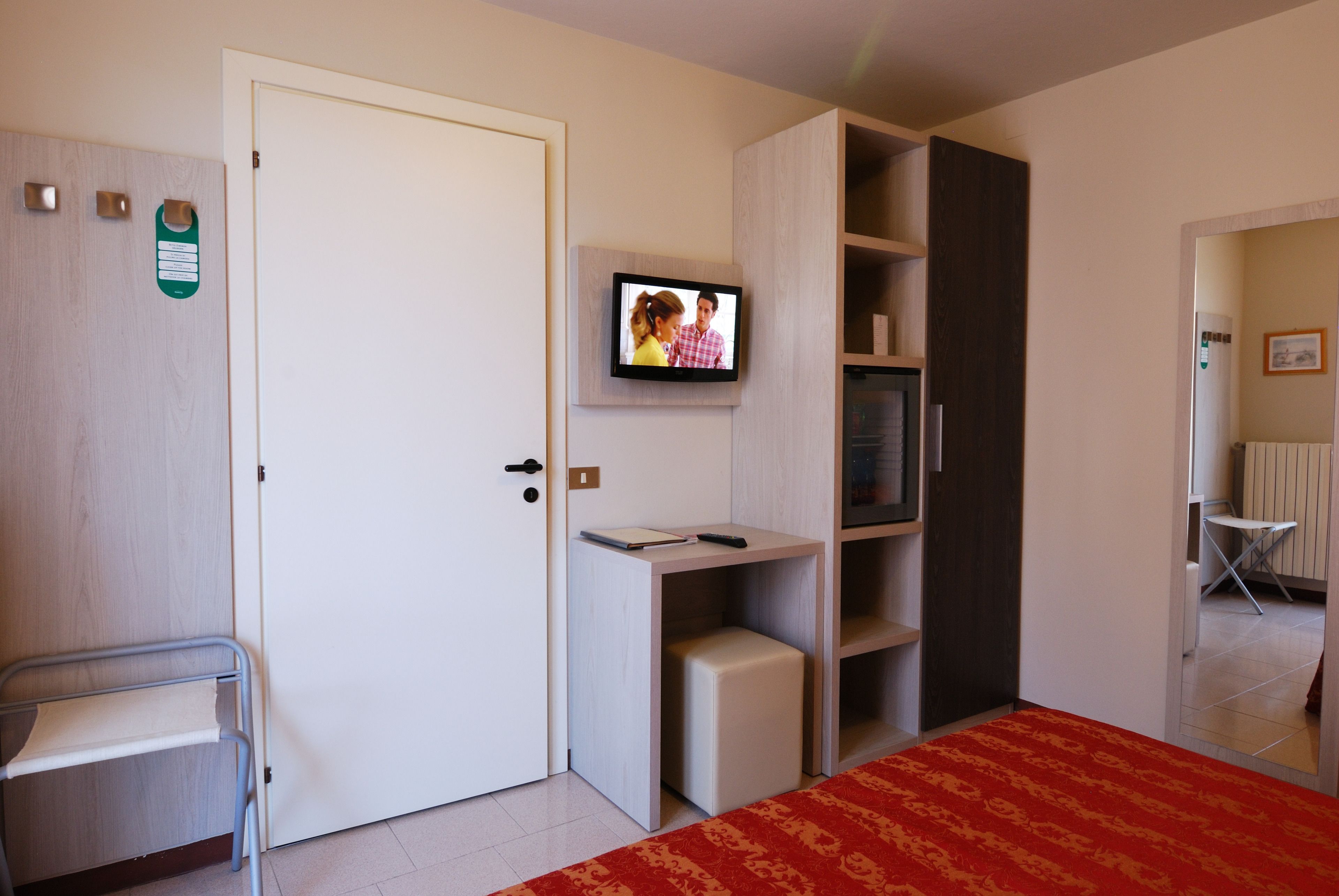 A room with a bed, a desk, a television, a chair, and a wardrobe.