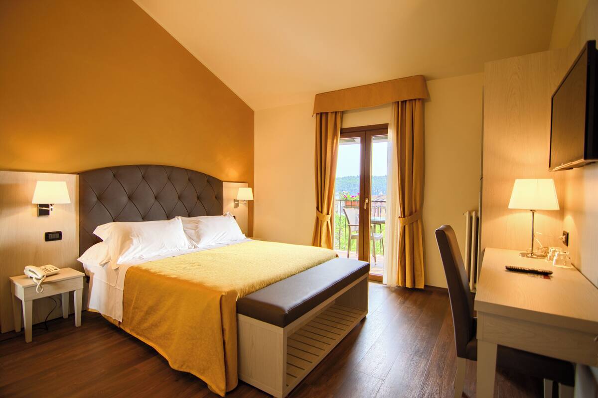 Habitación de hotel con una cama grande, un escritorio, una silla y vistas al exterior.