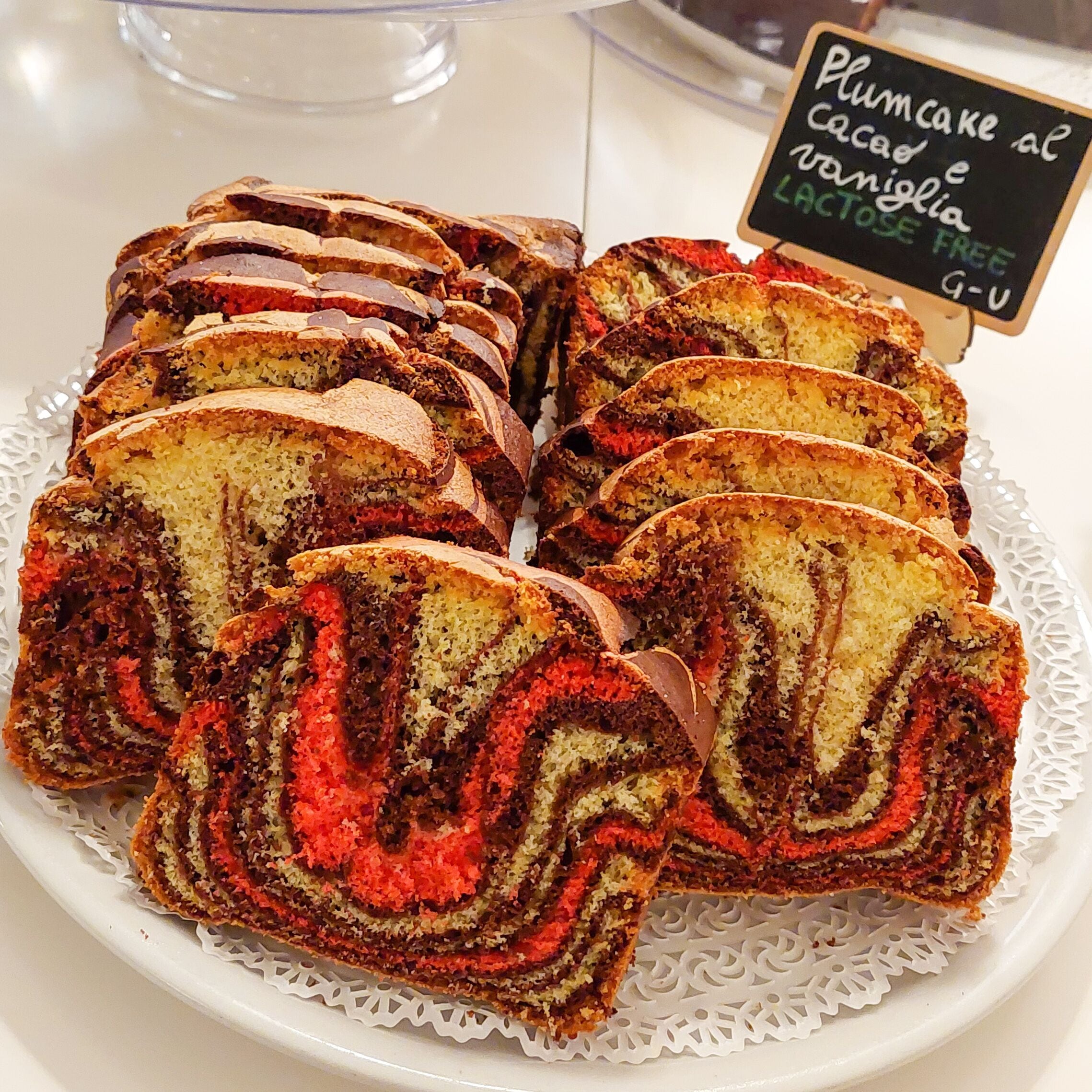 A display of sliced plum cake rolls on a white plate with a lace doily.