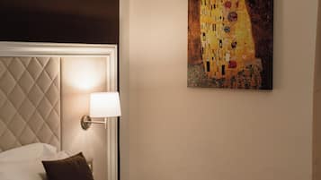 A hotel room with a bed, a headboard, a wall-mounted lamp, and a painting.
