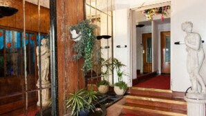 Un vestíbulo con alfombra roja, suelo de madera, una estatua y plantas en macetas.