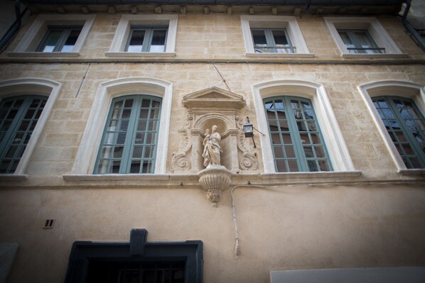 A building facade with arched windows, a central decorative element, and a door at the bottom. - La Banasterie (Avignon)