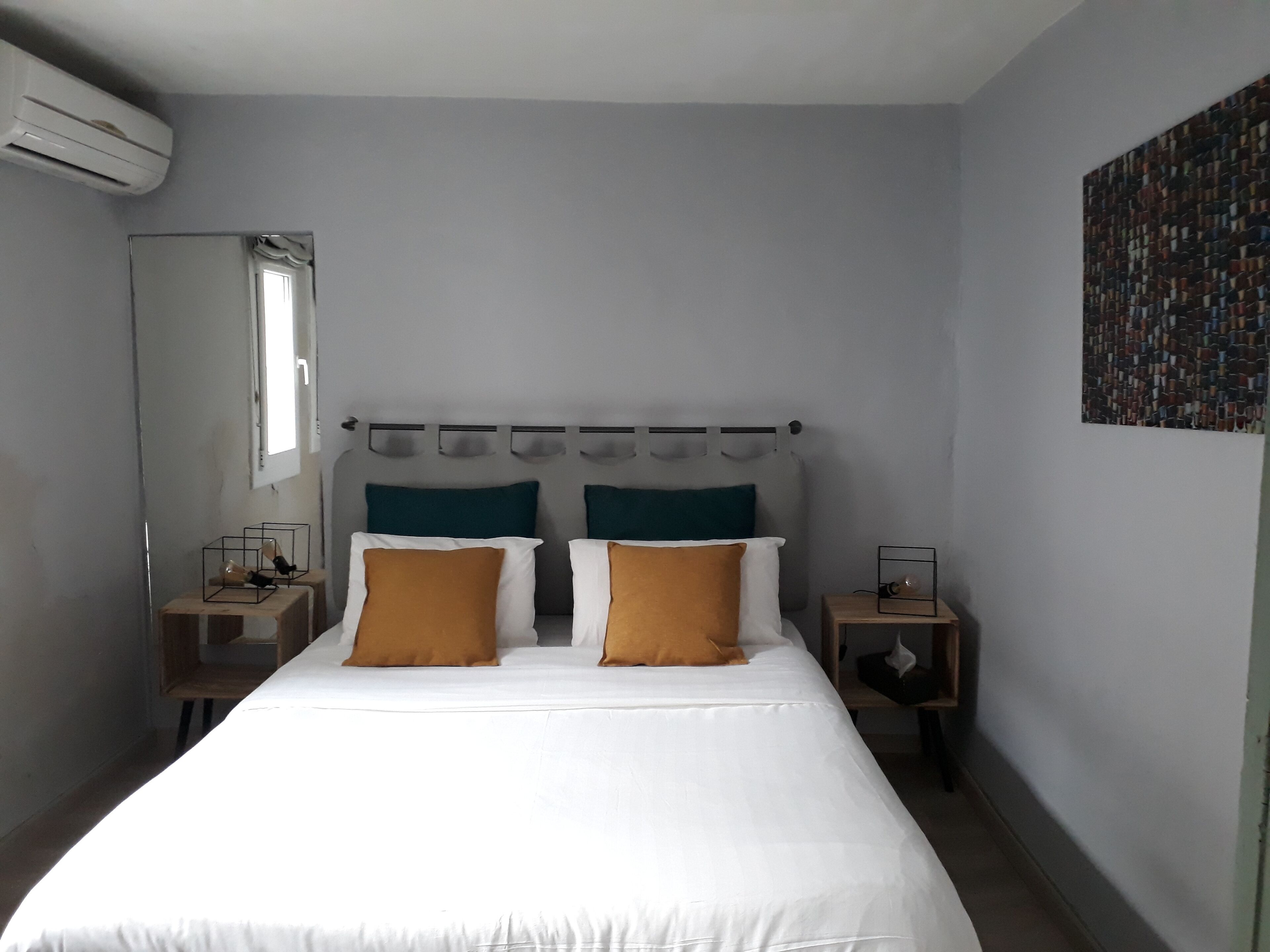 A bedroom with a bed, two nightstands, a mirror, and a wall art piece.
