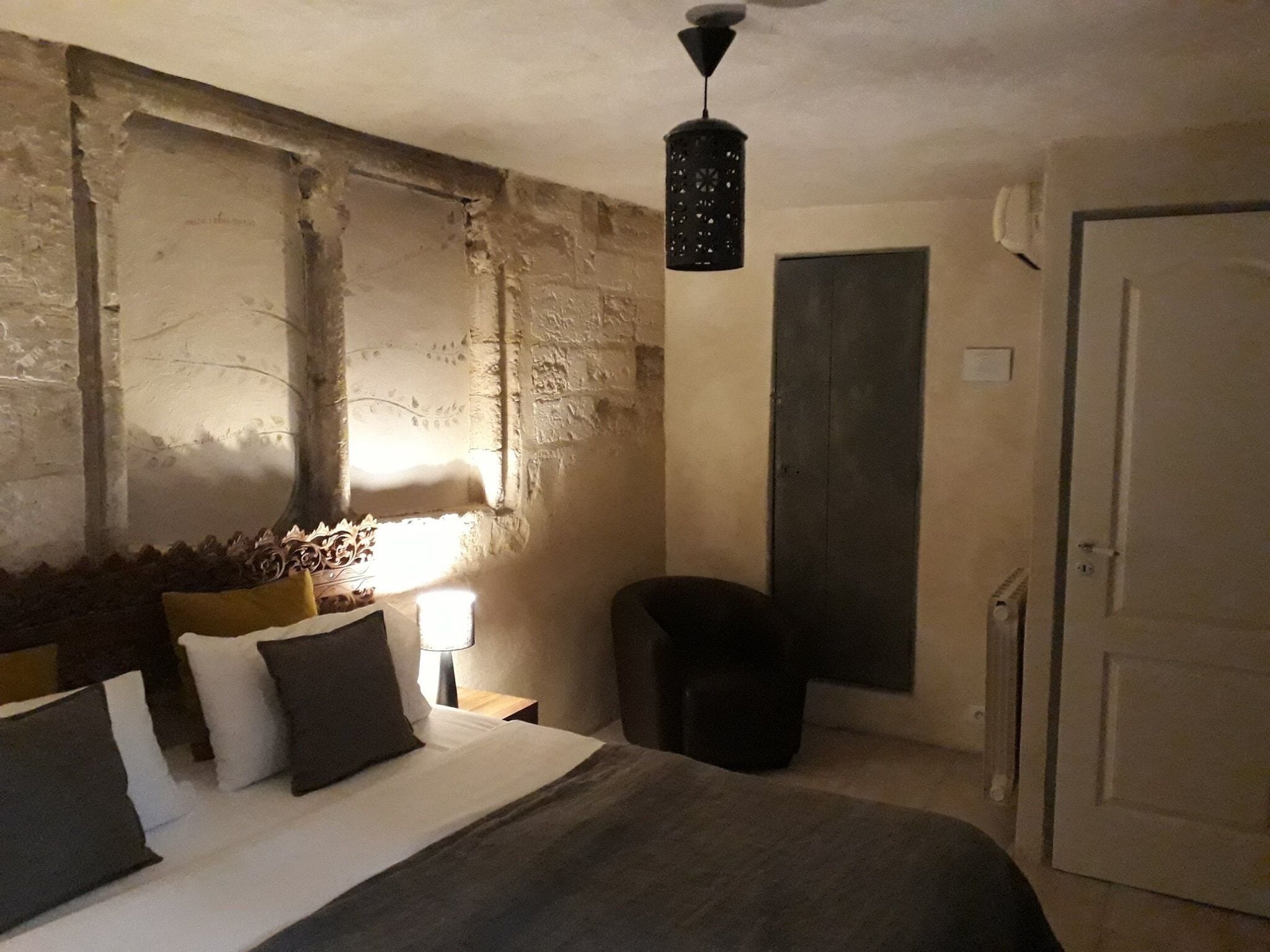 Une chambre à coucher avec un lit, une table de chevet, une lampe et une porte.
