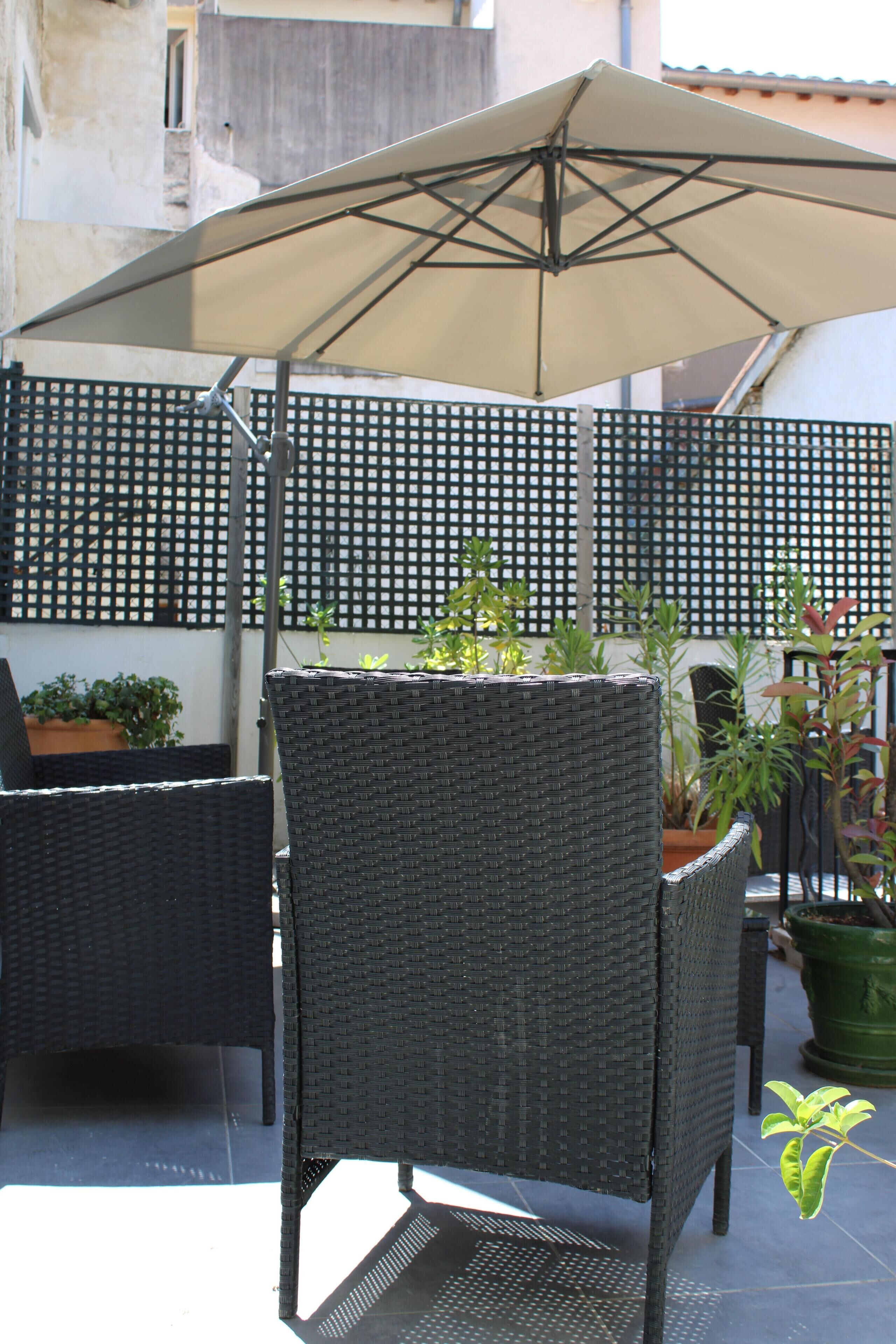 A patio area with wicker furniture, a table, and an umbrella.