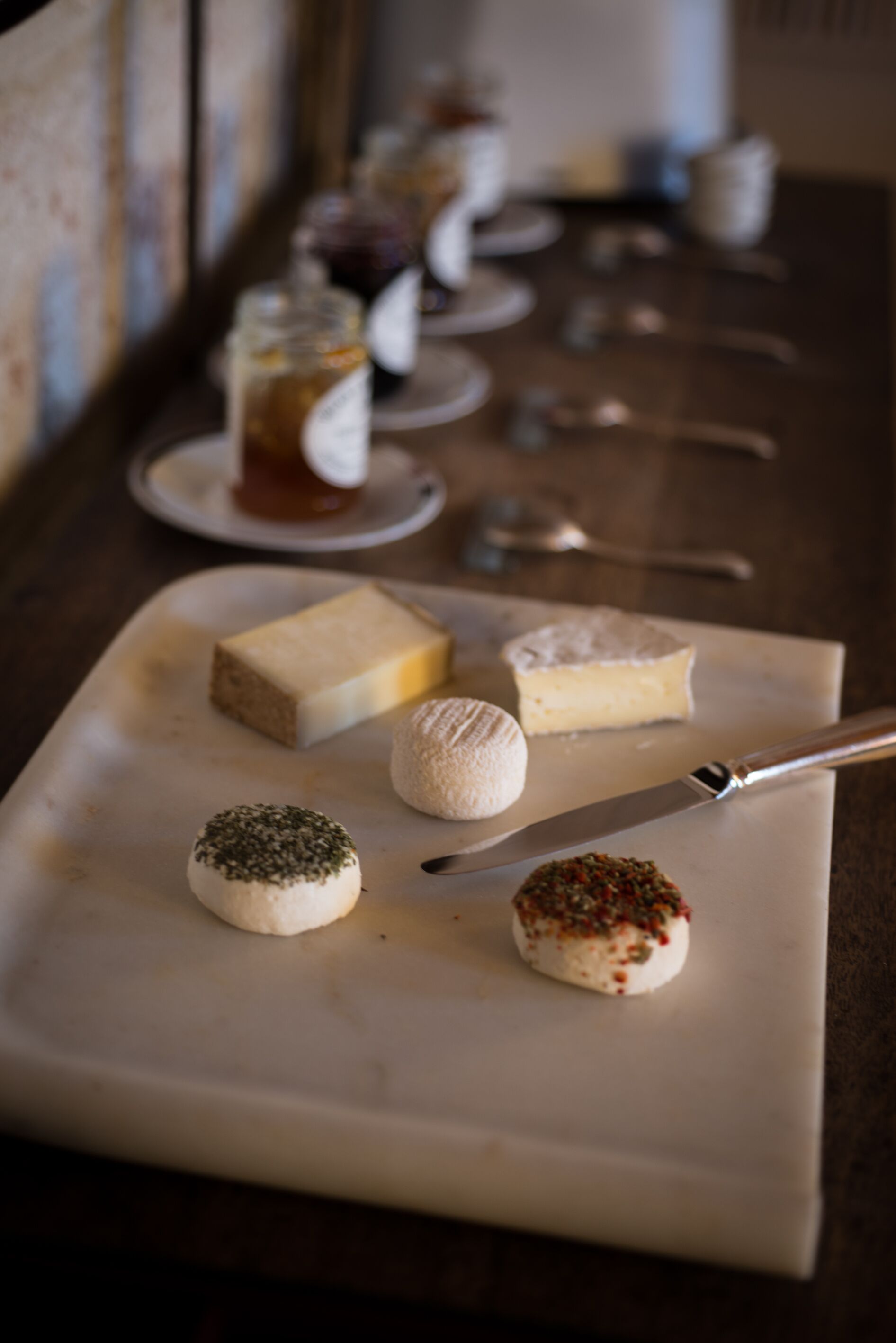 A variety of cheeses and condiments on a white cutting board.