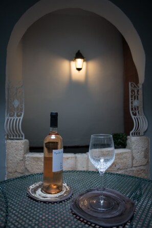 A table with a bottle of wine and a glass on a green tablecloth. - La Banasterie (Avignon)