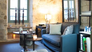 A cozy living room with a stone wall, a blue sofa, a round coffee table, and a bookshelf.