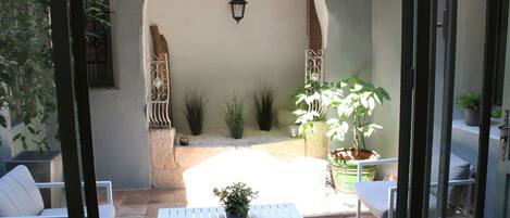 A patio with a white table and chairs, surrounded by potted plants and a decorative archway.