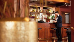 Een bar met een houten toonbank, flessenplanken en een persoon die aan de bar staat.