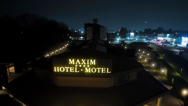 Een MAXIM HOTEL met een opvallend bord, een verharde inrit en een goed verlicht pad naar de ingang.