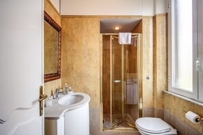 A bathroom with a glass-enclosed shower, a sink, and a toilet. - Astoria Palace (Rome)