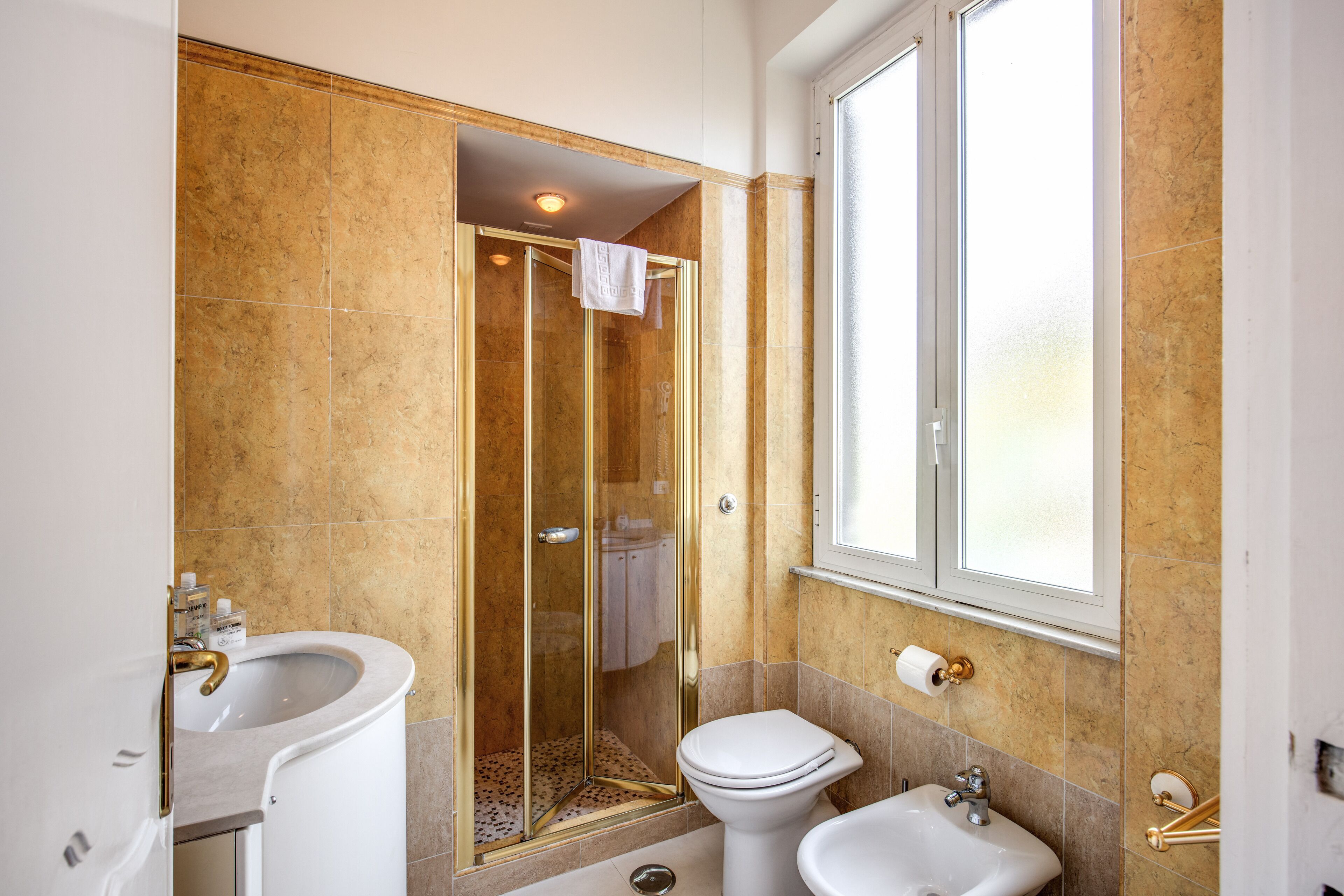 A bathroom with a glass-enclosed shower, a sink, and a toilet.