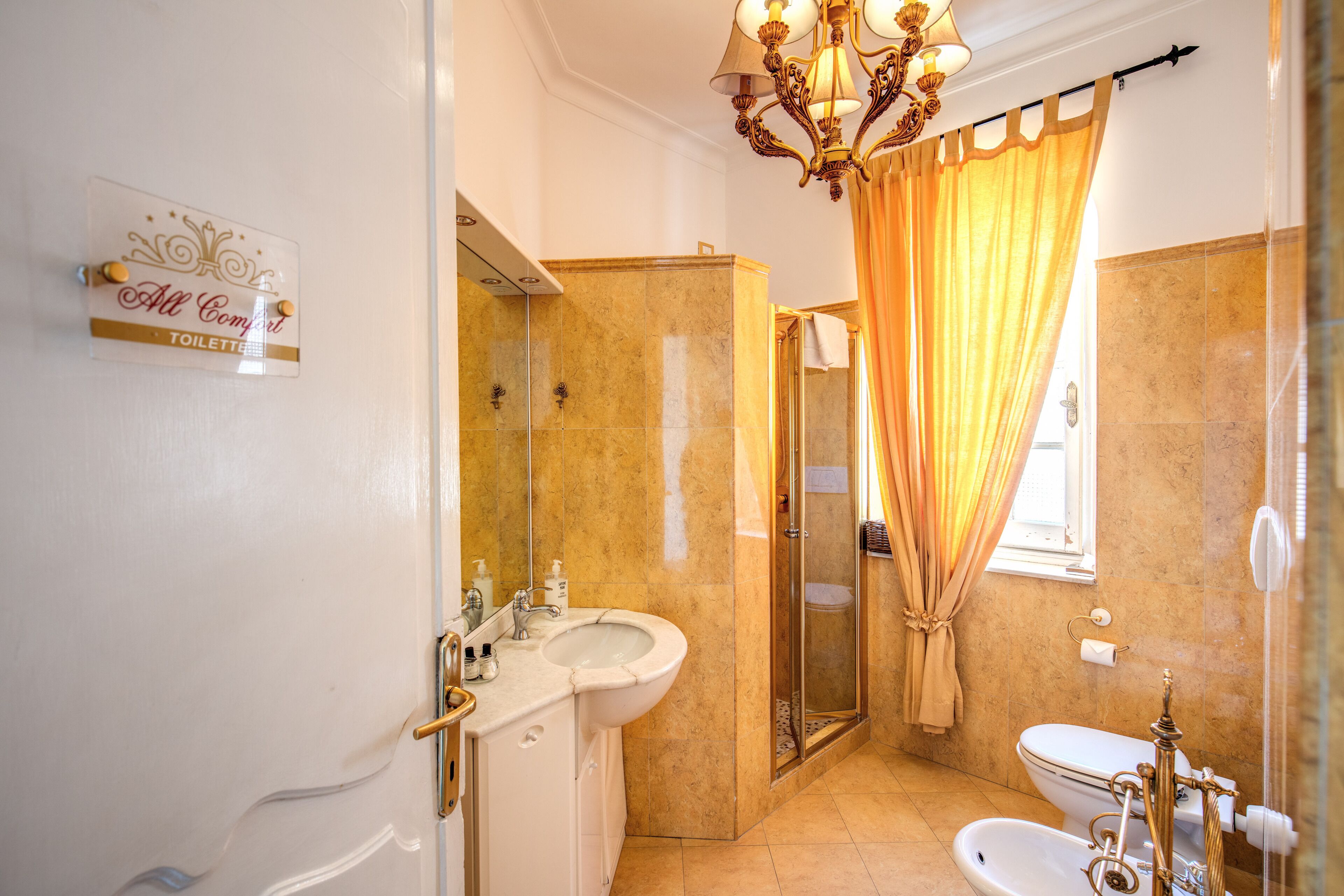 Une salle de bain équipée d’un lavabo, de toilettes et d’une douche. Un panneau sur le mur indique l’emplacement des toilettes.