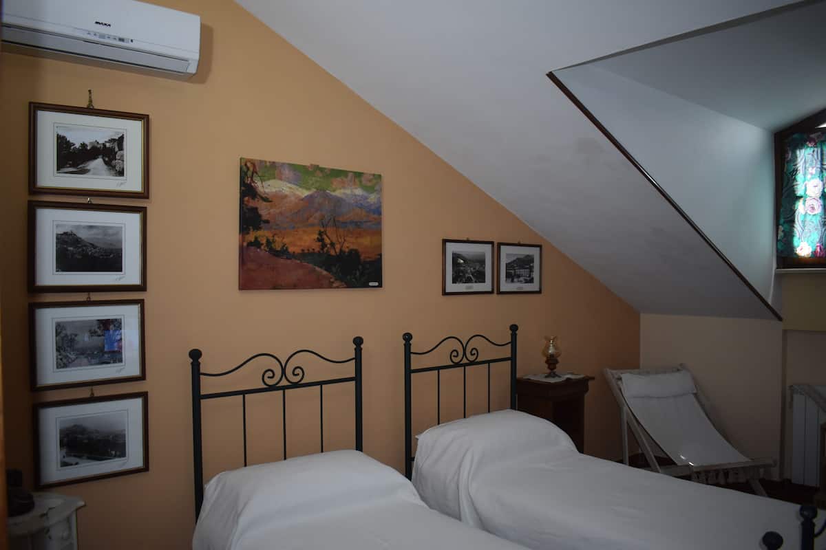 Ein Schlafzimmer mit zwei Betten, gerahmten Bildern an der Wand und einem Gemälde.