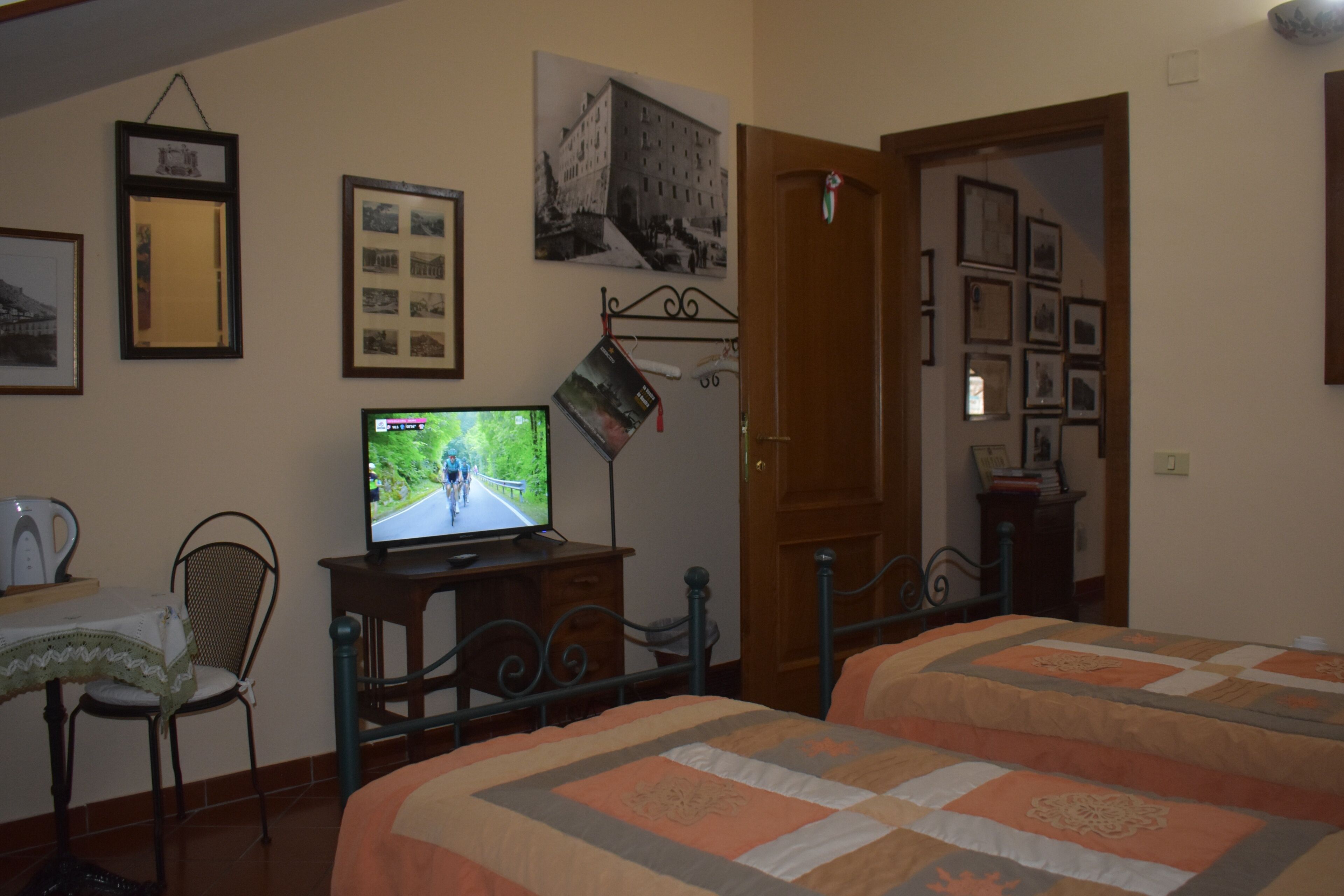 A bedroom with two beds, a television, a chair, and a table.