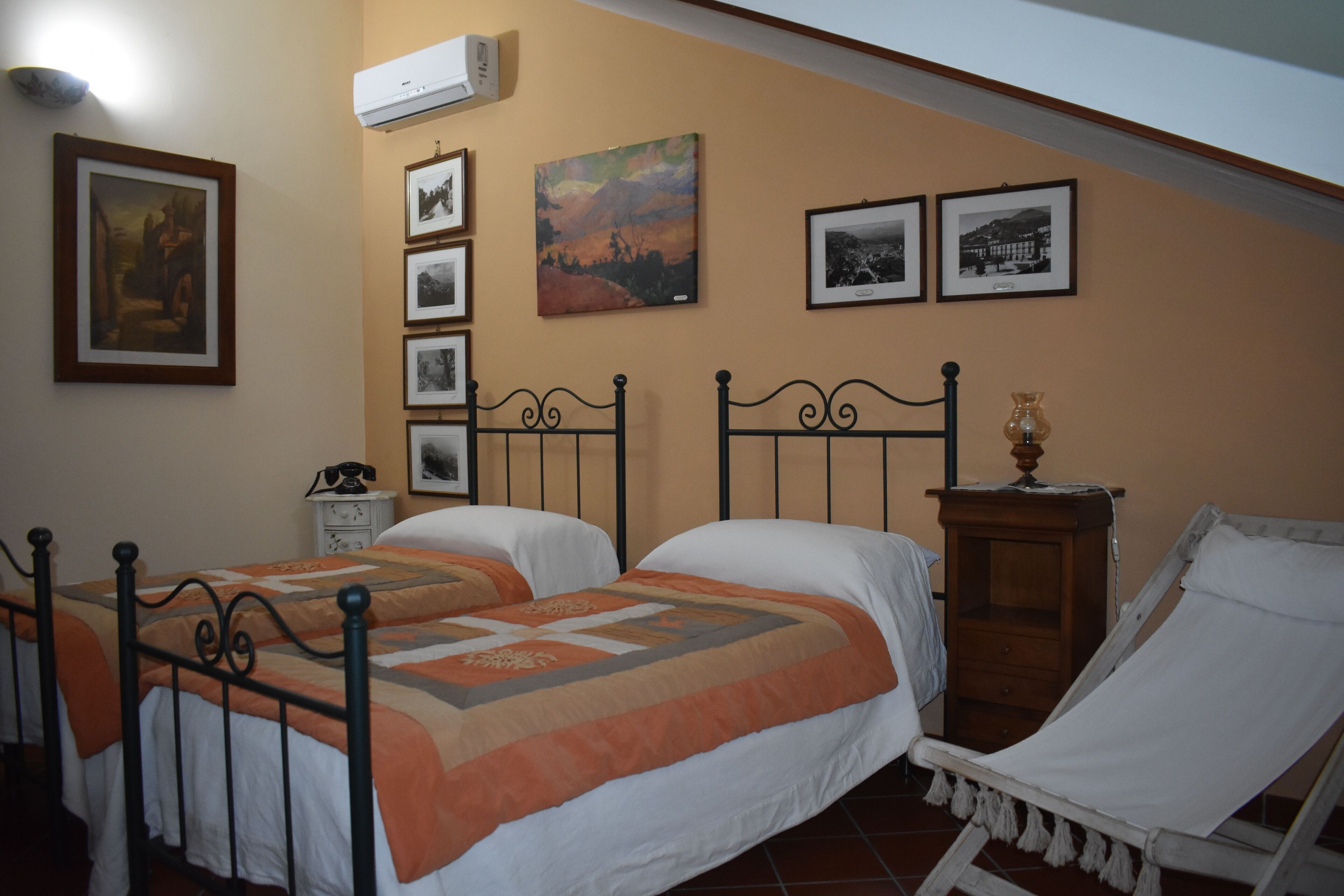 Quarto com duas camas, uma cadeira e uma mesinha de cabeceira.