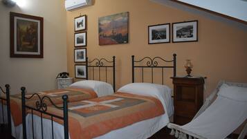 Quarto com duas camas, uma cadeira e uma mesinha de cabeceira.
