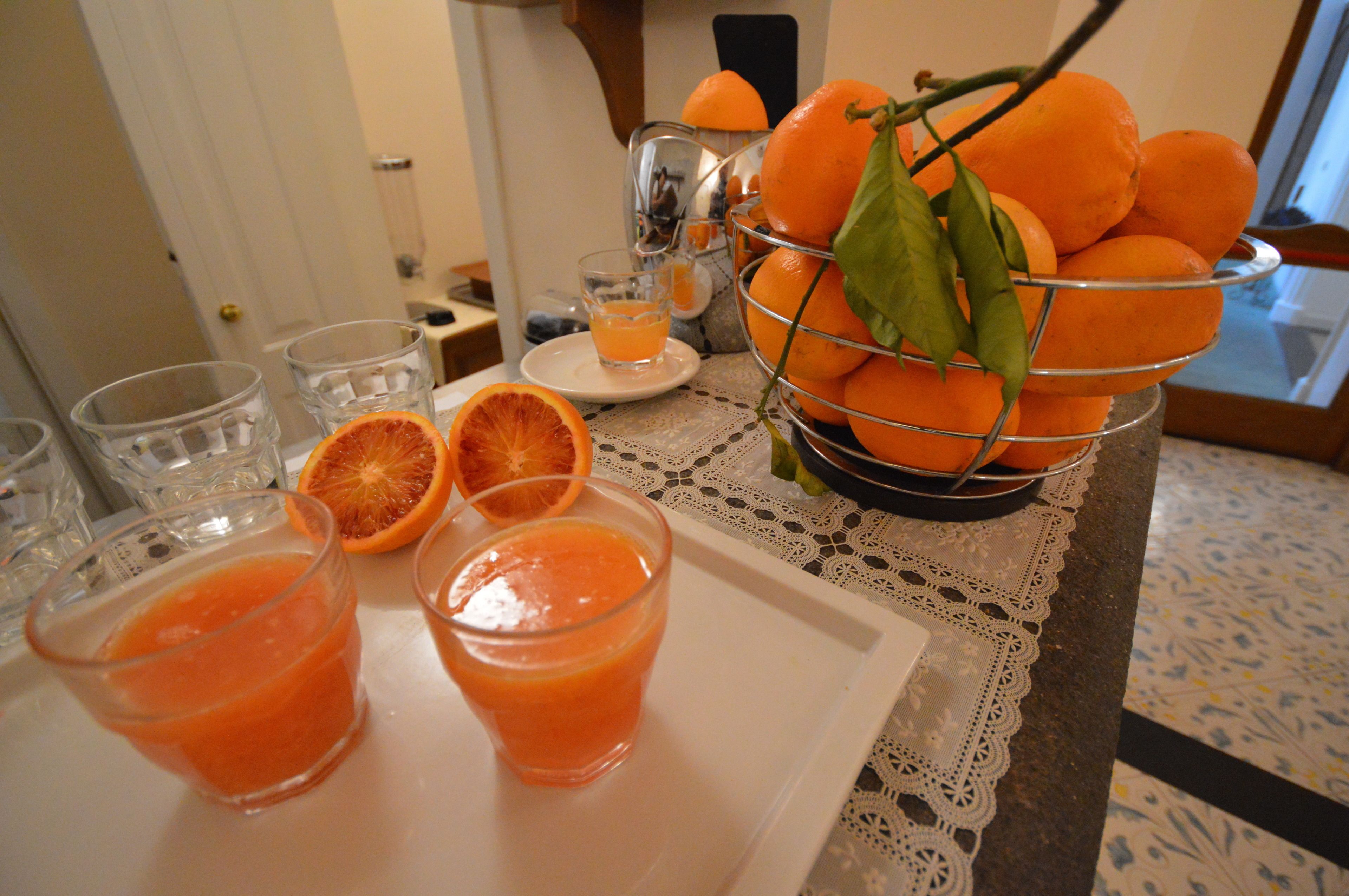 Una mesa con una bandeja de naranjas y un vaso de zumo de naranja.