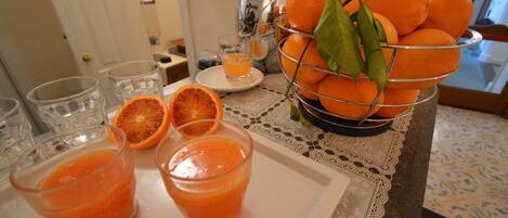 Una mesa con una bandeja de naranjas y un vaso de zumo de naranja.