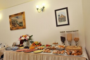 A buffet table with various food items and a vase of flowers. - L'Antico Convitto (Amalfi)