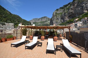Una terraza en la azotea con sillones de descanso, plantas en macetas y una pérgola.