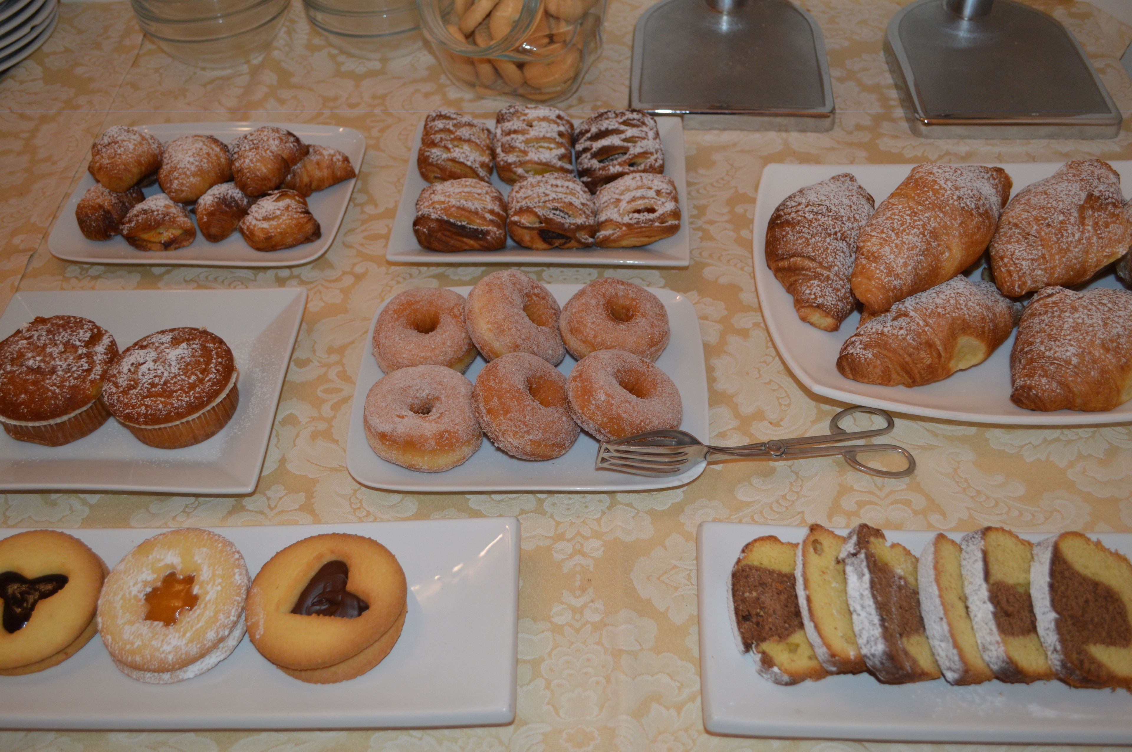 Een tafel met verschillende gebakjes en desserts, zoals donuts, muffins en taart.