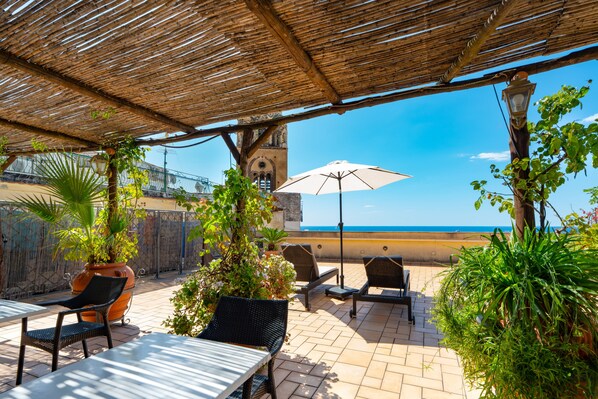 An outdoor patio with a view of the sea, featuring a table, chairs, and potted plants. - L'Antico Convitto (Amalfi)