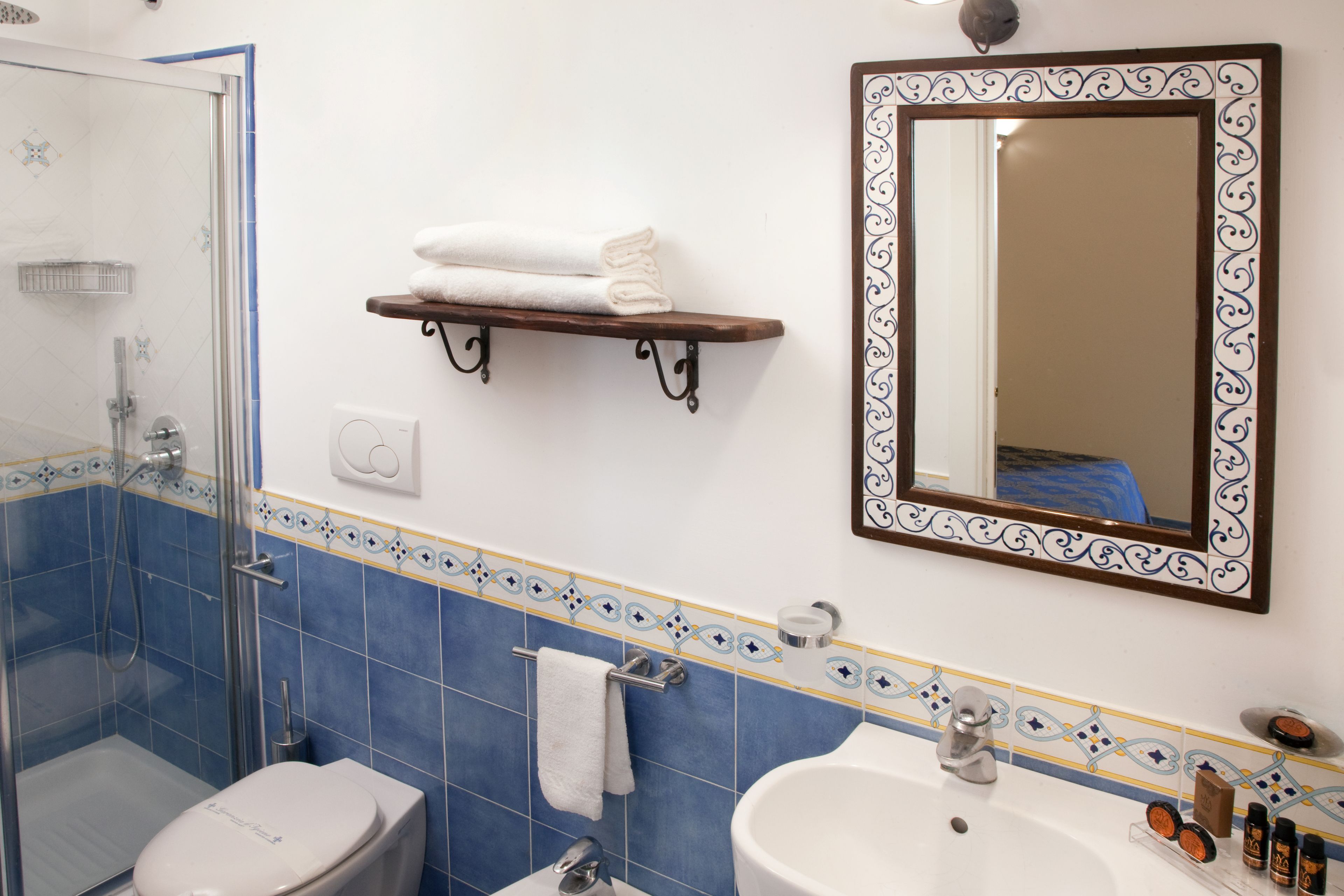 Une salle de bain équipée d’une douche, de toilettes, d’un lavabo et d’un miroir avec un cadre décoratif.