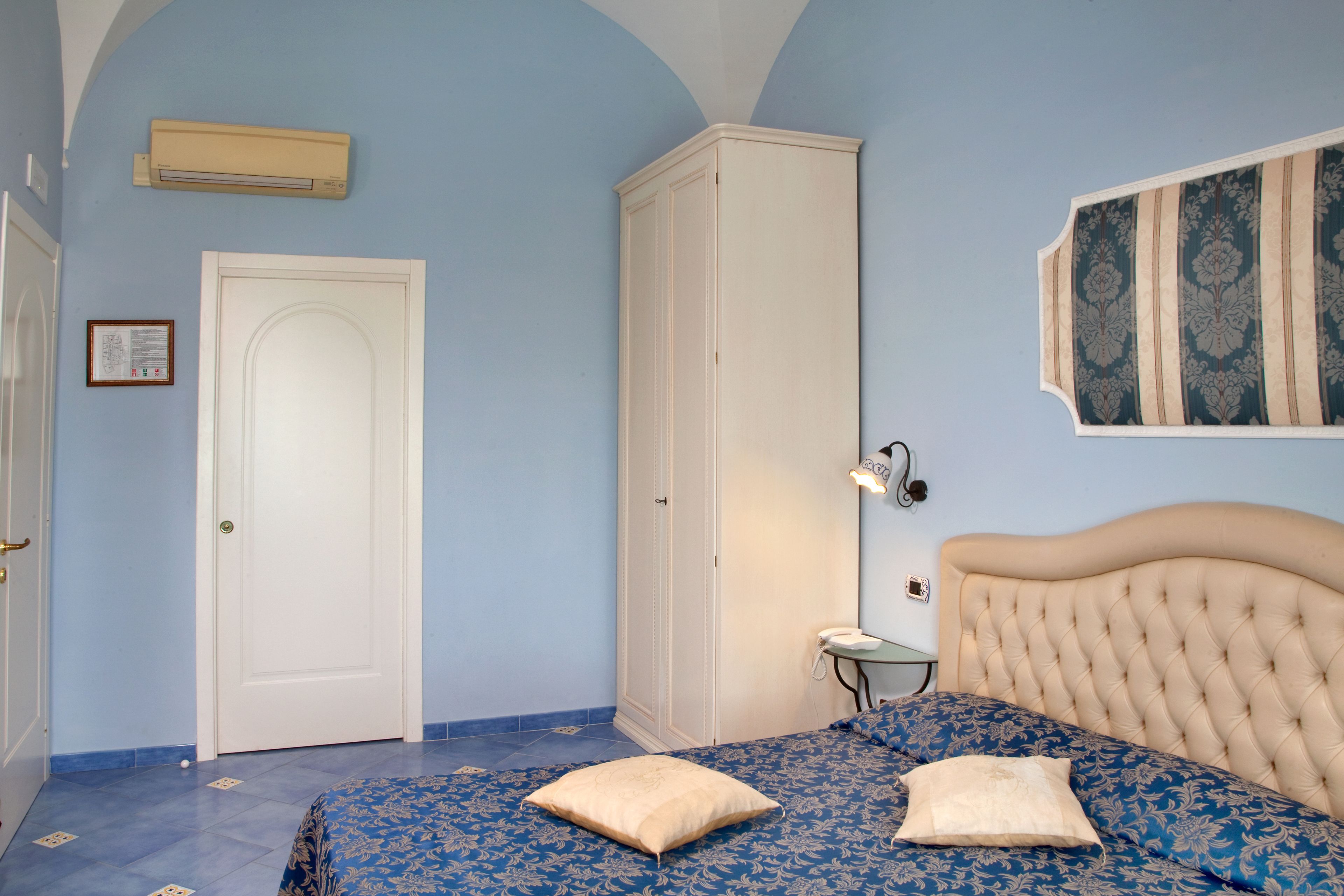 A bedroom with a bed, a wardrobe, a door, and a wall-mounted light fixture.