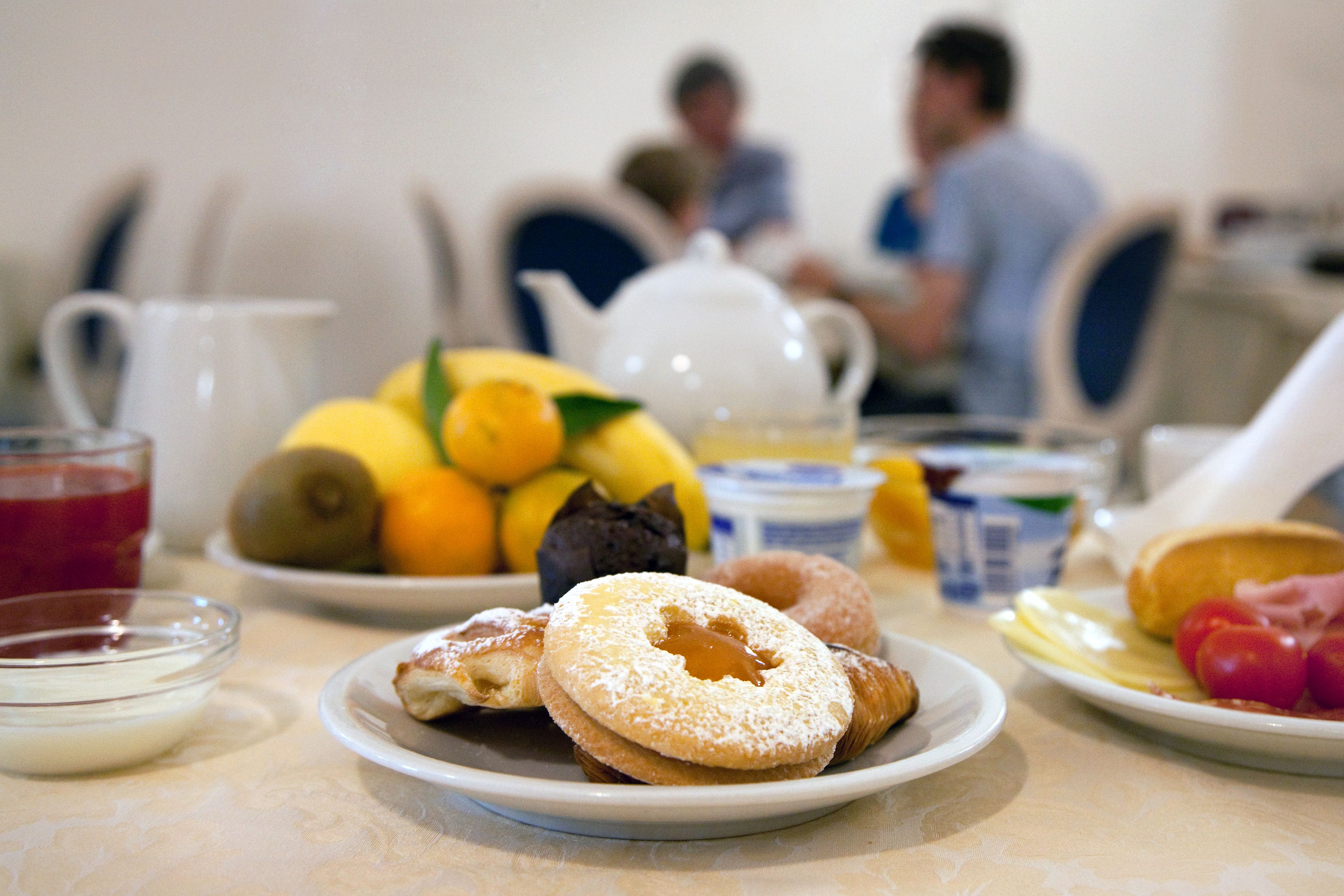 A breakfast table with various food items and a teapot.