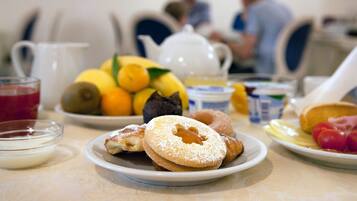 A breakfast table with various food items and a teapot.