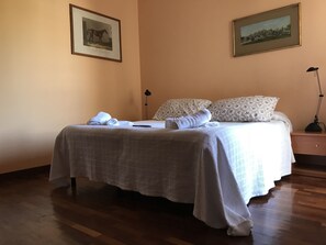 A neatly made bed with a white bedspread and two pillows, a bedside table with a lamp, and two framed pictures on the wall. - Le Finestre sul Vaticano (Rome)