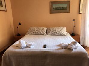 A neatly made bed with white linens, two bedside lamps, and a remote control on the bed. - Le Finestre sul Vaticano (Rome)