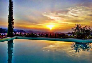 Una piscina al aire libre, sombrillas, sillones reclinables de piscina