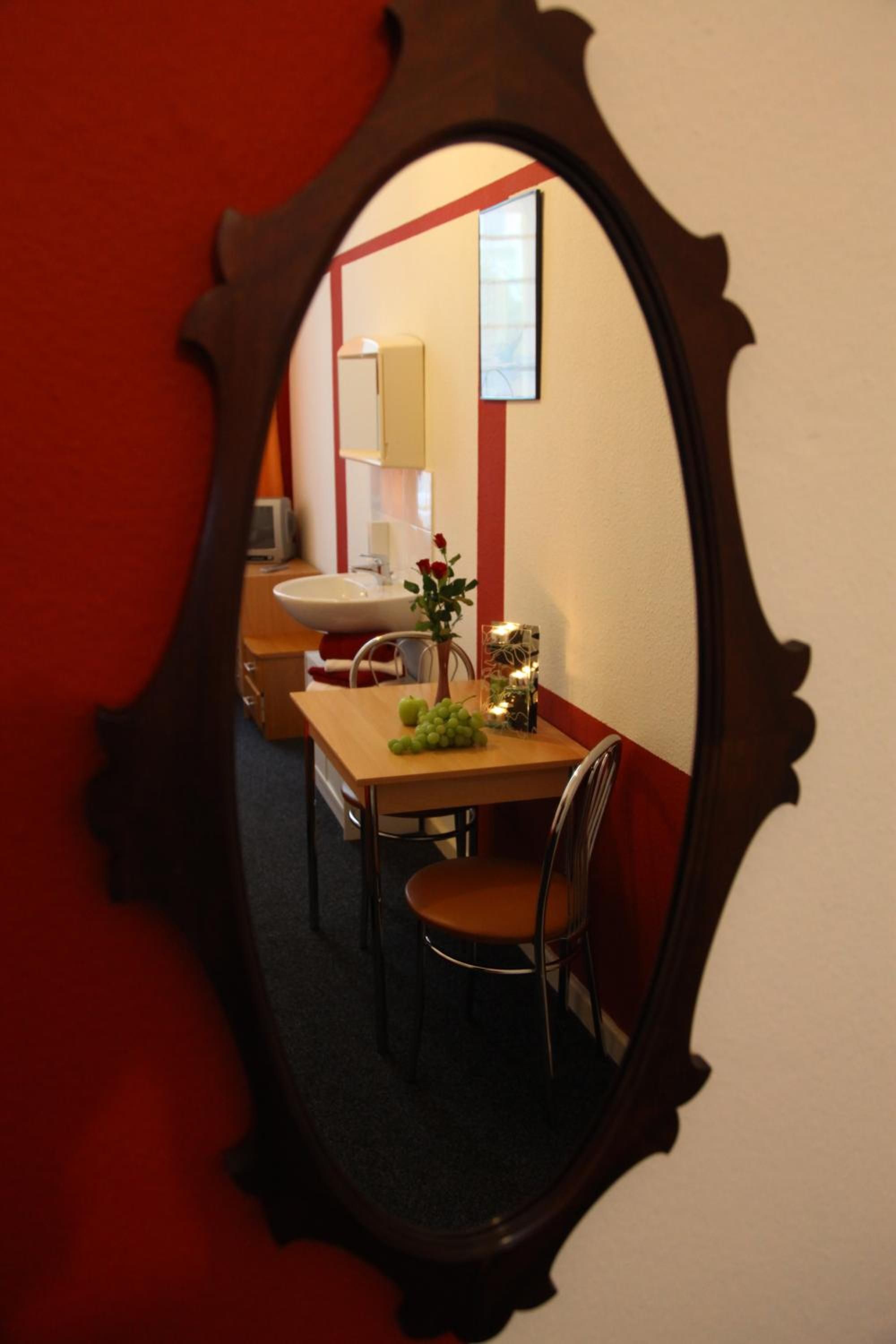 Ein Zimmer mit Esstisch, Stühlen, einem Spiegel und einem Waschbecken.