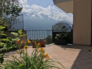A balcony with a view of the sea, potted plants, and a metal gate. - Villa Belvedere Hotel (Limone sul Garda)
