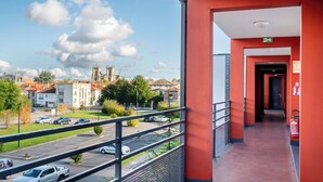Pasillo de hotel con fachada roja, vista a un estacionamiento e iglesia al fondo.