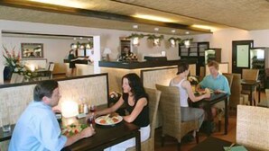Un ristorante con banquette e tavoli, alcuni dei quali con piante sopra.