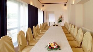 Una sala conferenze con un lungo tavolo, sedie e un centrotavola floreale.
