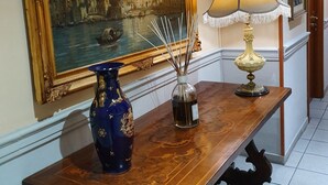 A hallway with a wooden table, a painting, a lamp, and a vase. - Hotel San Giorgio (Bergamo)