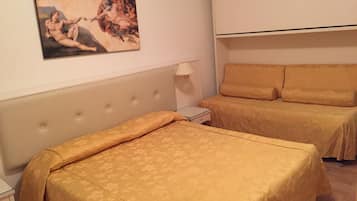 Hotellihuone, jossa on yksi sänky, sohva, yöpöytä ja taulu seinällä.