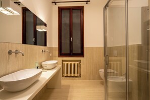 A modern bathroom with two sinks, a glass shower enclosure, and a window with a wooden frame. - Ca'Turelli Dimora Storica (Venice)