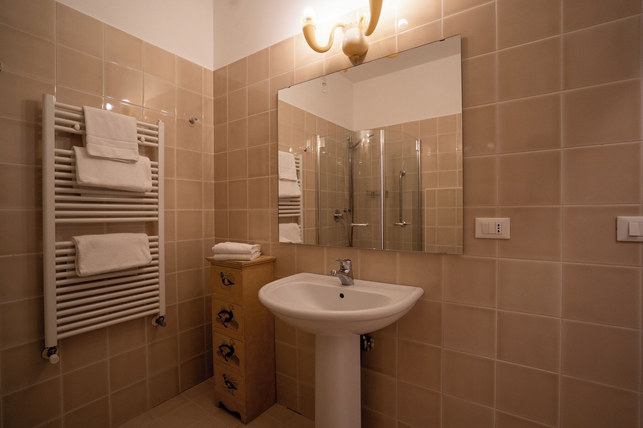 A bathroom with a white sink, a mirror, and a towel rack with folded towels.